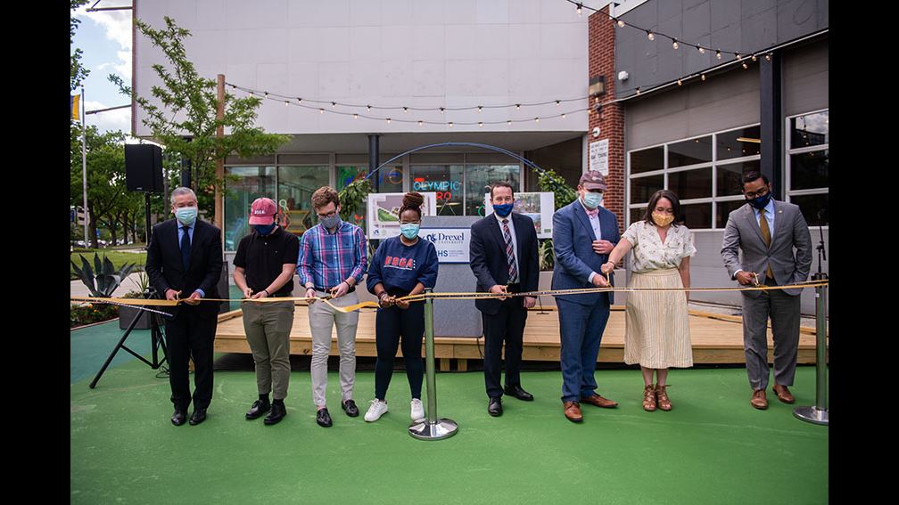 President John Fry at the Gateway Garden Ribbon Cutting ceremony. He is cutting the ribbon alongside various people.