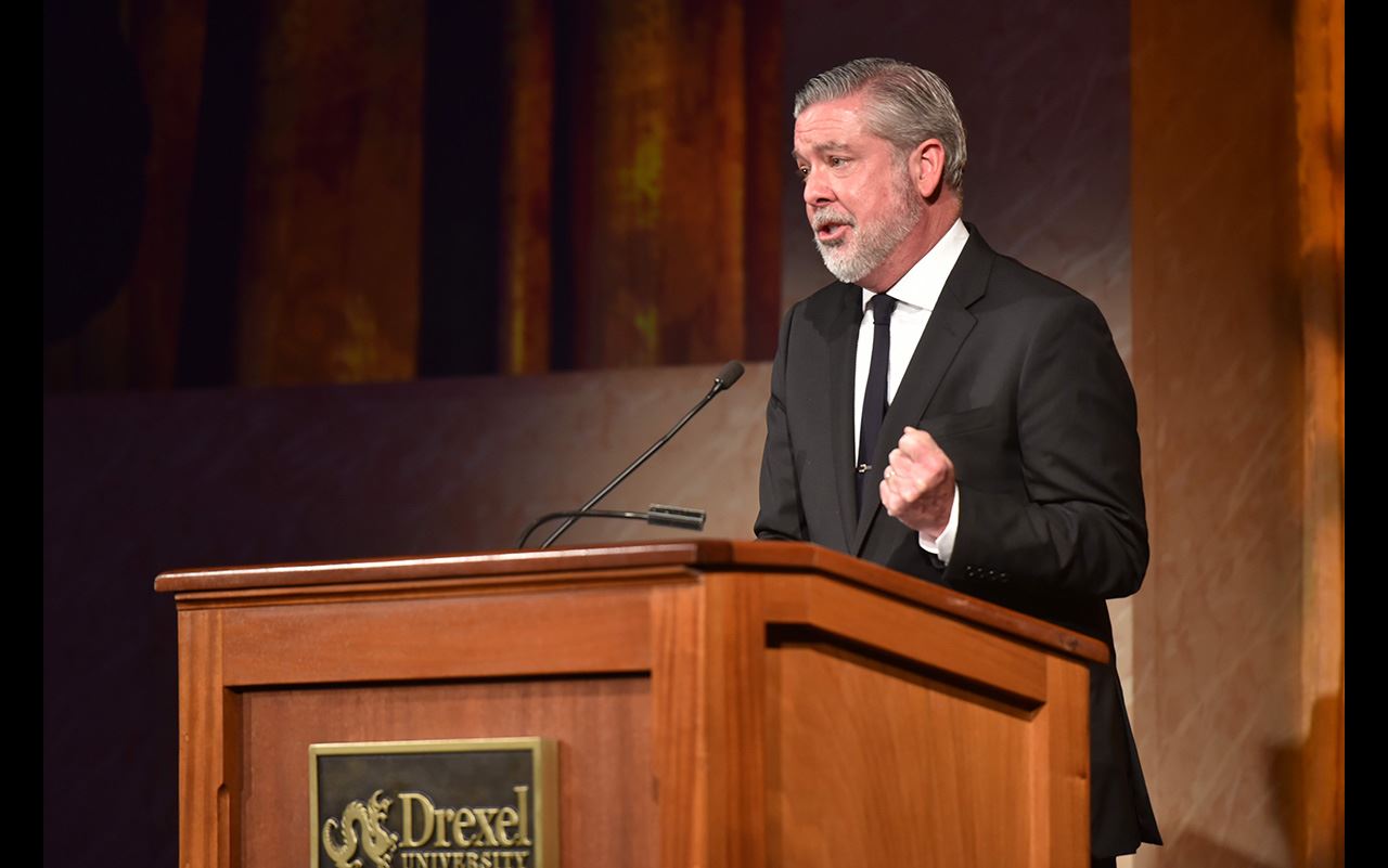 President John Fry standing in front of a podium where he makes a speech for the Business Leader of the Year event honoring Richard Green.
