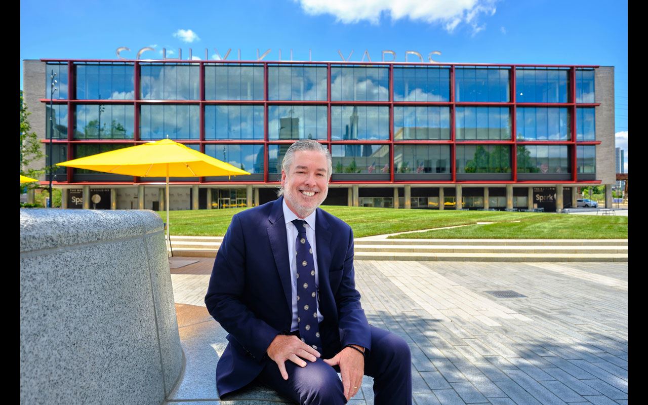 President John Fry sitting down, smiling in front of Drexel Square.