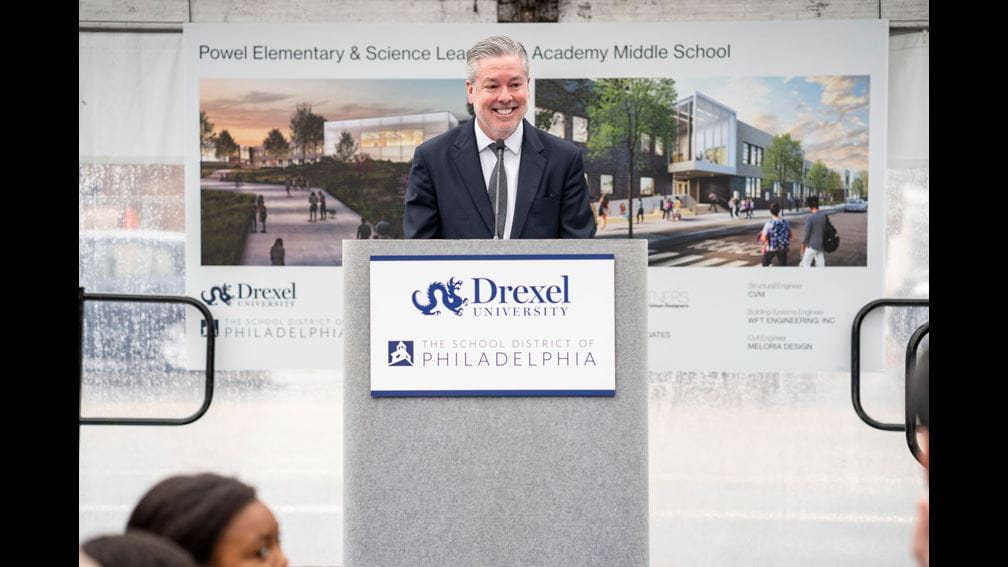 President John Fry standing and smiling in front of the podium at the K8 School Groundbreaking event.