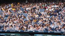 Students in Commencement regalia, some with ponchos and umbrellas, in the stands of Citizens Bank Park for Drexel&#39;s 2024 Commencement.